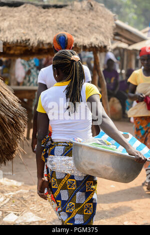 BOHICON, BENIN - Jan 12, 2017: Unbekannter beninischen Frau mit Zöpfe trägt ein Becken auf dem lokalen Markt. Benin Menschen leiden unter der Armut aufgrund der Stockfoto