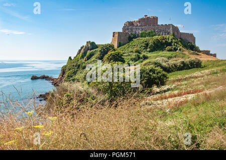 Wilde Blumen füllen den Vordergrund mit Mont Orgueil Castle oberhalb der Stadt Gorey auf der Insel Jersey im Hintergrund. An einem Sommertag. Stockfoto