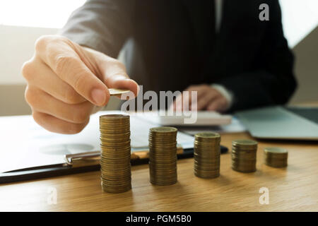 Geschäftsmann nimmt Münzen auf den Tisch und zählt Geld. Geschäftskonzept. Stockfoto