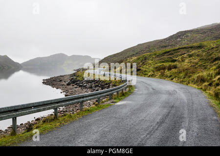 Das ist ein Bild von einem geschwungenen Mountain Lake Road im Morgennebel. Dieser See ist als See Salz und ist in Donegal Irland Stockfoto