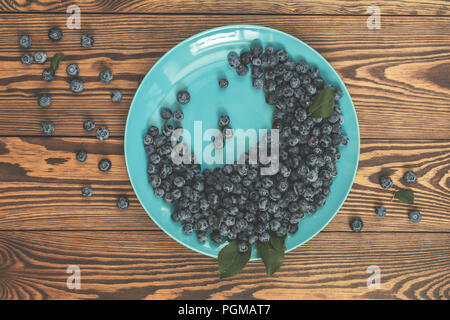 Vielen saftigen schönen erstaunlich schöne Blaubeeren in blau Teller auf dunklem Hintergrund. Schönes essen Kunst Hintergrund. Ansicht von oben, kopieren. Stockfoto