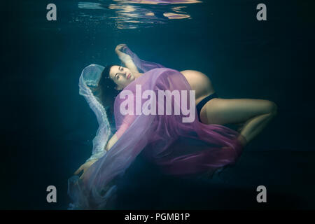 Porträt einer wunderschönen schwangere junge Frau unter Wasser. Stockfoto