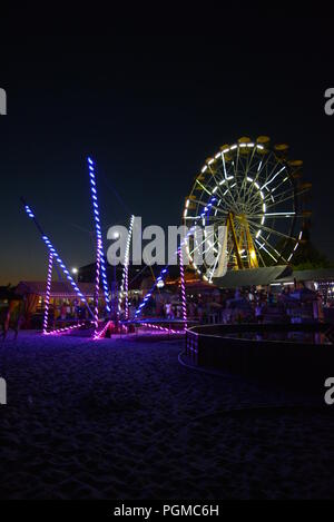 Am Strand des Schwarzen Meeres mit Kinderbecken, Trampolin mit Diodenbändern und Sonnenschirmen entlang der Küste. Stockfoto