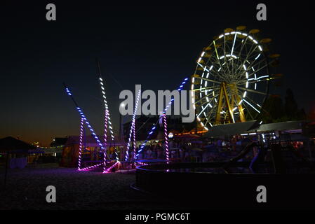 Am Strand des Schwarzen Meeres mit Kinderbecken, Trampolin mit Diodenbändern und Sonnenschirmen entlang der Küste. Stockfoto