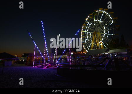Am Strand des Schwarzen Meeres mit Kinderbecken, Trampolin mit Diodenbändern und Sonnenschirmen entlang der Küste. Stockfoto