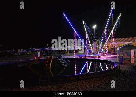 Am Strand des Schwarzen Meeres mit Kinderbecken, Trampolin mit Diodenbändern und Sonnenschirmen entlang der Küste. Stockfoto