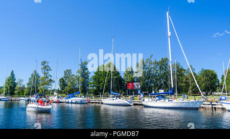 Karlsborg, Schweden - Juli 2, 2018: Familie anreisen im Motorboot zu den Gota canal Marina in der Stadt. Festgebundene Segelboote im Hintergrund. Ein gewöhnlicher sonnig Stockfoto