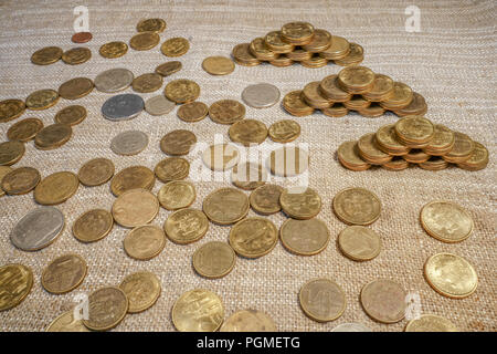 Die goldenen und silbernen Münzen verstreut und auf eine Pyramide Tabelle angeordnet Stockfoto