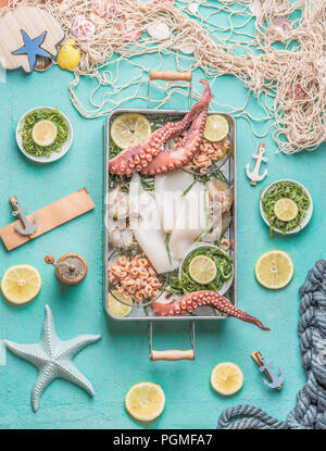 Verschiedene Meeresfrüchte in Fach auf hellblauem Hintergrund mit Fischnetz, Algen und Zutaten, Ansicht von oben. Meeresfrüchte Konzept Stockfoto