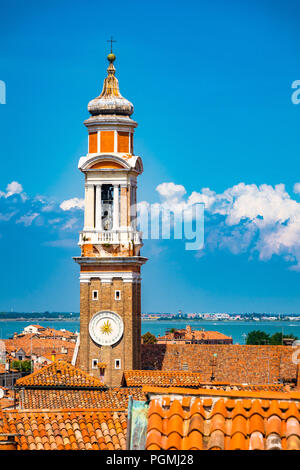 Ein Backsteinglockenturm (Campanile), geschmückt mit einer schönen Uhr aus der Kirche Chiesa Cattolica Parrocchiale dei Santi Apostoli in Venedig, Italien Stockfoto