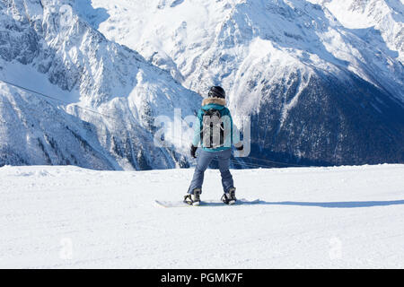 Ein snowboarder Mädchen reitet auf einem Hintergrund der Berge im Winter. Sport Art von Urlaub. Das Konzept der Snowboarden, Erfolg, lifestyl Stockfoto