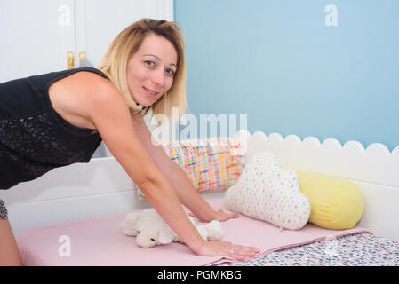 Junge Frau, die die kinder Bett Stockfoto