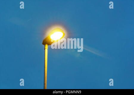 Lampe leuchtet auf leere Wanderweg in Abend, und strahlend blauer Himmel Stockfoto