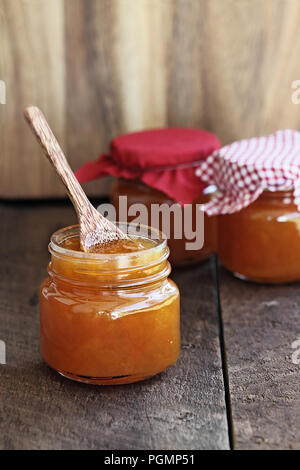 Holzlöffel in einem hausgemachten jar von Melone Marmelade mit zwei anderen Gläser im Hintergrund. Extrem flache Tiefenschärfe mit selektiven Fokus auf enthalten Stockfoto