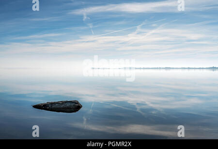 Einen Felsen auf eigene im Strangford Lough mit schönen Reflexionen der Wolken an einem blauen Himmel. Stockfoto