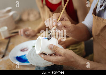 Männliche potter Holding Malerei Pinsel beim Dekorieren Tontopf Stockfoto