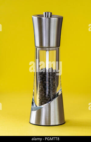 Edelstahl und Glas Pfeffer Mühle auf gelbem Hintergrund. Stockfoto