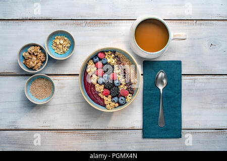 Gesundes Frühstück. Smoothie Schale mit Früchten, Nüssen, Müsli und eine Tasse Kaffee auf schäbige weiße Holzvertäfelung. Flach, Ansicht von oben. Stockfoto