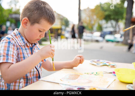 Cute little boy Zeichnung mit bunten Farben im Herbst Park. Kreative Kind malen auf Natur. Aktivität im Freien für Kleinkind Kind. Begabte Kind Schmerzen Stockfoto