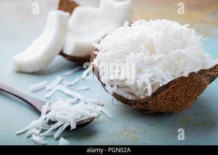 Kokosraspeln in einer Muschel auf blauem Hintergrund. Stockfoto