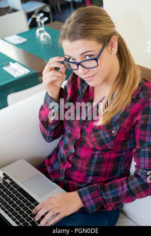 Junges Mädchen mit Laptop an der Kamera, die in der Bar Stockfoto