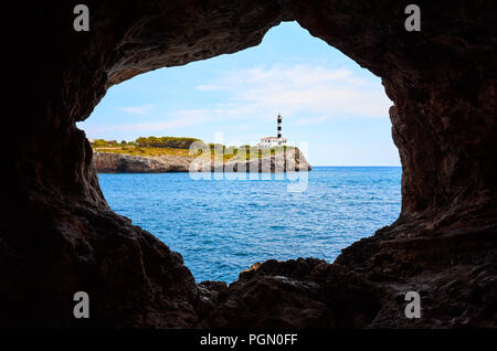 Portocolom Leuchtturm auf einer Klippe aus einer Höhle, Mallorca, Spanien gesehen. Stockfoto
