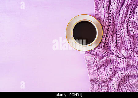 Tasse heißen Kaffee auf Violett Tabelle, Nahaufnahme Foto in Form gestrickter Pullover mit Becher, Winter morgen Konzept. Ansicht von oben. Flach Stockfoto