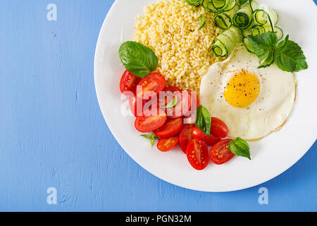 Gesundes Frühstück. Diätetisches Menü. Millet Porridge und Tomaten, Gurken Salat und gebratene Eier. Ansicht von oben. Flach Stockfoto