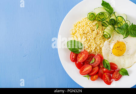 Gesundes Frühstück. Diätetisches Menü. Millet Porridge und Tomaten, Gurken Salat und gebratene Eier. Ansicht von oben. Flach Stockfoto