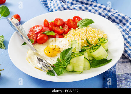 Gesundes Frühstück. Diätetisches Menü. Millet Porridge und Tomaten, Gurken Salat und gebratene Eier. Stockfoto