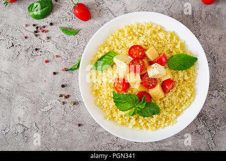 Millet Porridge mit Käse, Butter und Basilikum in weiße Schüssel. Leckeres Essen. Frühstück. Ansicht von oben. Flach Stockfoto