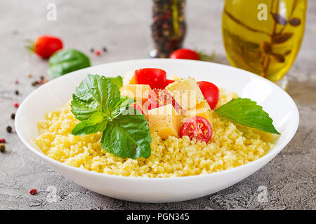 Millet Porridge mit Käse, Butter und Basilikum in weiße Schüssel. Leckeres Essen. Frühstück. Stockfoto