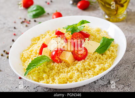 Millet Porridge mit Käse, Butter und Basilikum in weiße Schüssel. Leckeres Essen. Frühstück. Stockfoto
