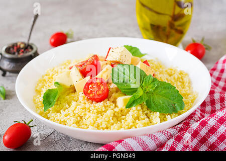 Millet Porridge mit Käse, Butter und Basilikum in weiße Schüssel. Leckeres Essen. Frühstück. Stockfoto