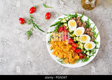 Nudelsalat mit frischem Gemüse, Eier und Thunfisch in einer weißen Schüssel. Mittag essen. Ansicht von oben. Flach Stockfoto
