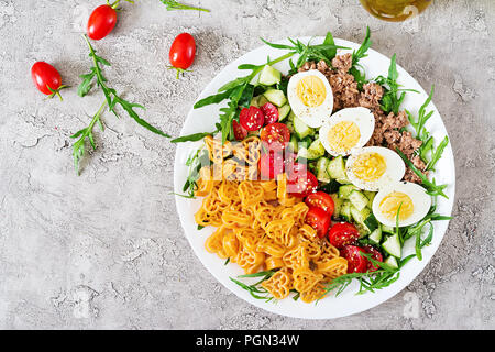 Nudelsalat mit frischem Gemüse, Eier und Thunfisch in einer weißen Schüssel. Mittag essen. Ansicht von oben. Flach Stockfoto