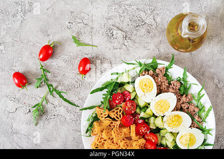 Nudelsalat mit frischem Gemüse, Eier und Thunfisch in einer weißen Schüssel. Mittag essen. Ansicht von oben. Flach Stockfoto