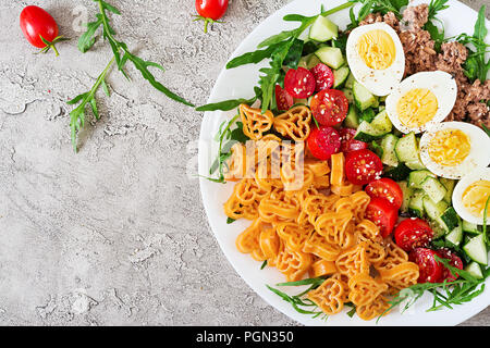 Nudelsalat mit frischem Gemüse, Eier und Thunfisch in einer weißen Schüssel. Mittag essen. Ansicht von oben. Flach Stockfoto