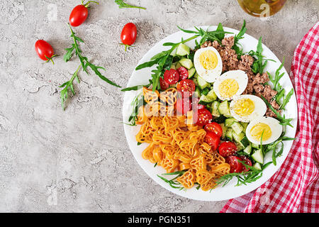 Nudelsalat mit frischem Gemüse, Eier und Thunfisch in einer weißen Schüssel. Mittag essen. Ansicht von oben. Flach Stockfoto