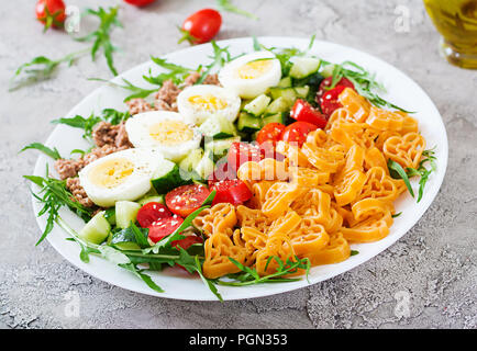 Nudelsalat mit frischem Gemüse, Eier und Thunfisch in einer weißen Schüssel. Mittag essen. Stockfoto