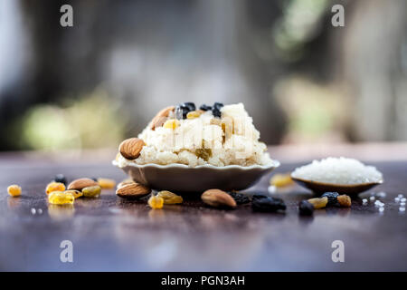 Beliebte indische und asiatische Dessert Suji ka Halwa oder Rava mit Bio Mandeln, Cashews und schwarz-goldenen raisns in einem Ton Schüssel auf Holz- Oberfläche. Stockfoto