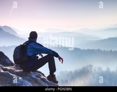 Müde tourist sitzt auf der Kante einer Klippe in die Ferne schauen. Wanderer ruht auf Mountain Trail. Unglaubliche Aussicht vom Gipfel. Stockfoto