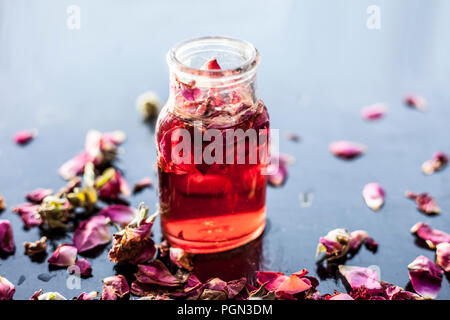 Rose Wasser oder Gulab jal oder Gulab ka Pani oder Rosa Wasser in einer Flasche auf Holz- Oberfläche mit Rosenblättern. Stockfoto