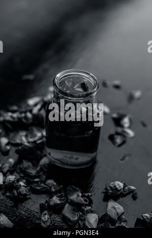 Rose Wasser oder Gulab jal oder Gulab ka Pani oder Rosa Wasser in einer Flasche auf Holz- Oberfläche mit Rosenblättern. Stockfoto