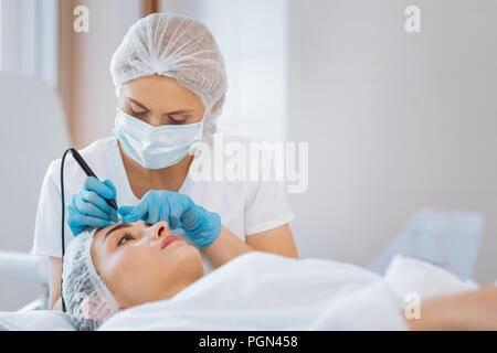 Professionelle ernste Dermatologe an der Patienten Gesicht Stockfoto