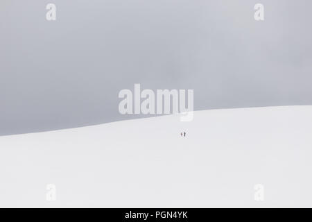 Ein sehr minimalistisches Blick auf zwei weit entfernte Menschen über einen Berg von Schnee bedeckt Stockfoto