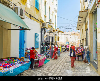 SOUSSE, TUNESIEN - 28. AUGUST 2015: Die schmale Straße von Kleidungsstück Markt neben den Stadtmauern der alten Medina, am 28. August in Sousse. Stockfoto