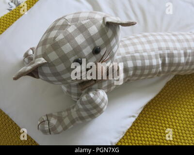 Dieses Spielzeug Tuch cat, in einem Karo style Material, Faulenzen ist auf dem Bett Stockfoto
