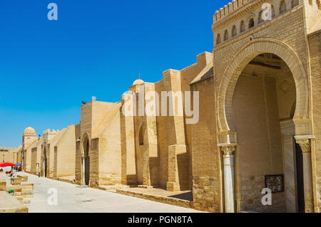 Die äußere massive Wand der Großen Moschee mit Türmen und Toren, mit Hufeisen arabischen Bögen und antiken römischen Säulen, Kairouan, Tunesien eingerichtet. Stockfoto