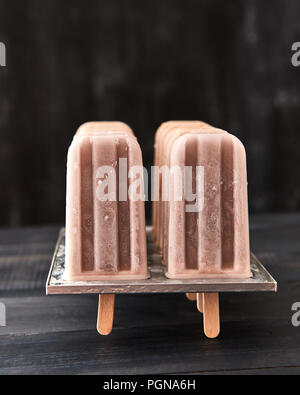 Hausgemachte Schokolade Eis lolly in einer Form, auf einem schwarzen Hintergrund mit Kopie Raum aus Holz Stockfoto